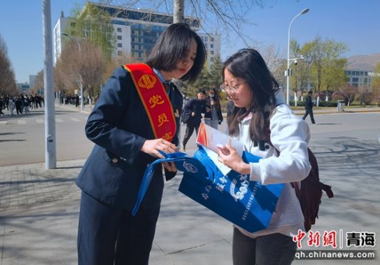 图为税务局工作人员向大学生发放宣传手册，现场讲解税收政策、税法知识。张海雯摄