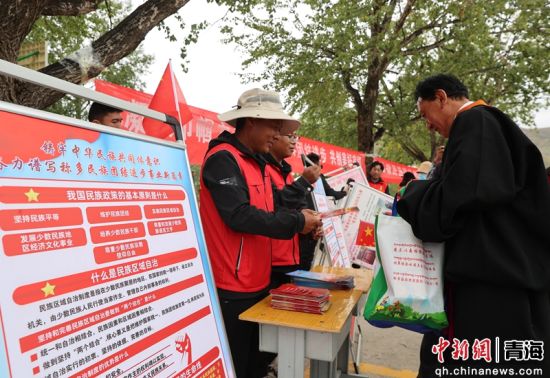 图为工作人员向现场观众发放民族团结进步知识宣讲资料。潘雨洁 摄